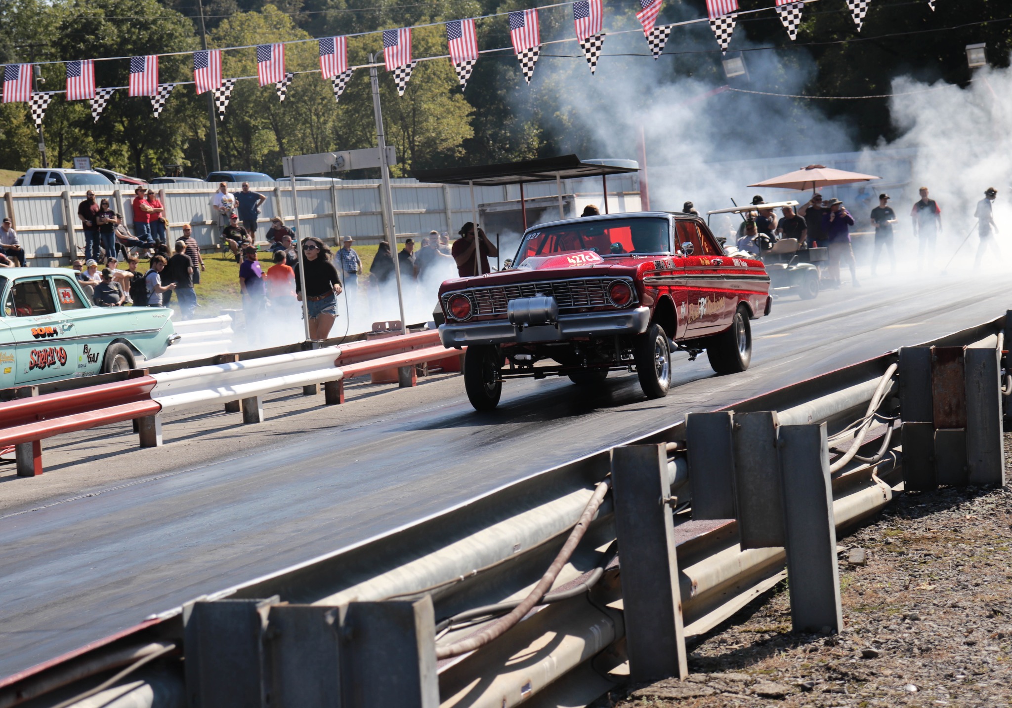 Red vintage drag car launching through tire smoke